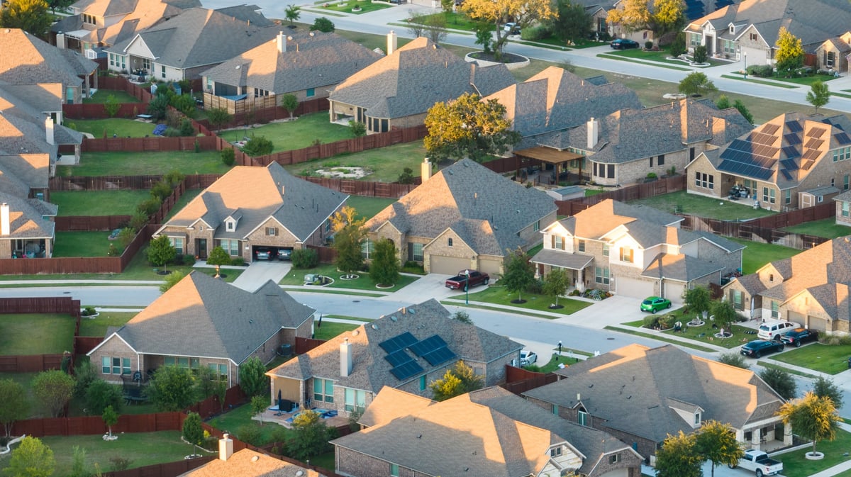 Aerial sunrise view of a new suburban neighborhood with houses and rooftop solar panels