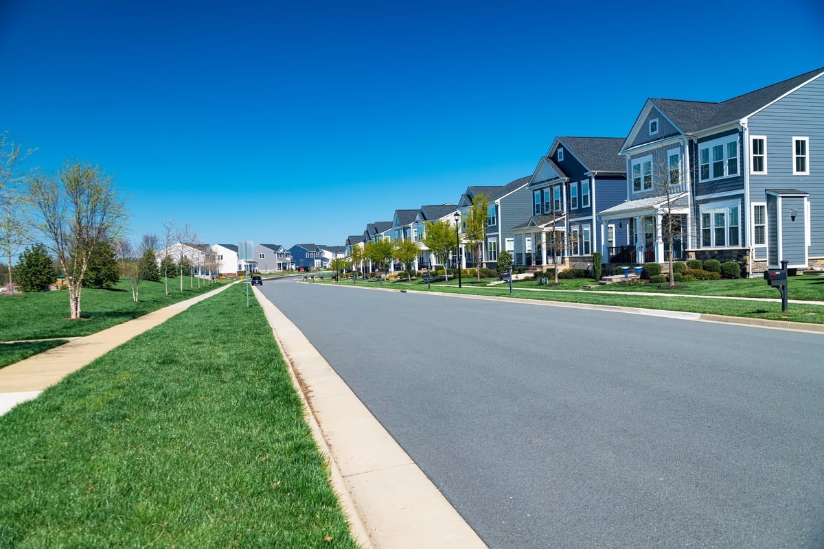 A row of modern detached houses along a road with lawn and sidewalk
